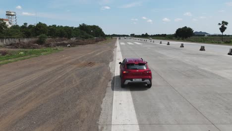 a cinematic aerial shot captures a car stopping along a bustling highway with the impressive sight of an emergency landing runway constructed on nh16 at chennai-vijayawada highway.