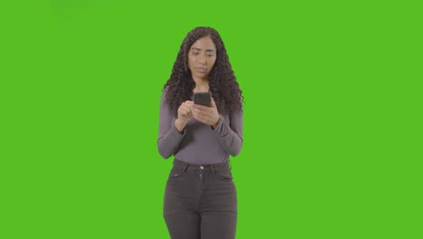 woman looking at mobile phone and celebrating good news against green screen 4