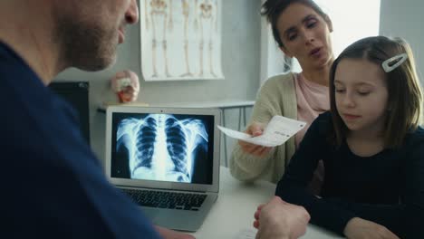 caucasian mother and daughter on visit at a general practitioner who is writing a prescription