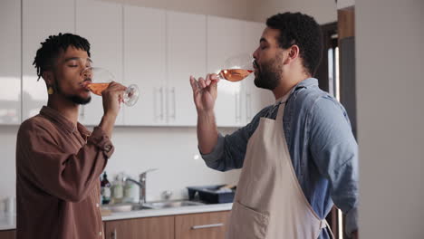 friends celebrating with rose wine in kitchen