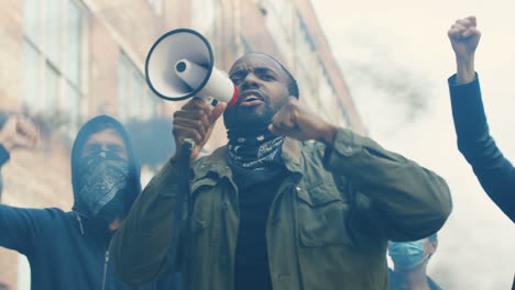 lower view of african american man yelling on a loudspeaker in a protest with multiethnic group of people in the street