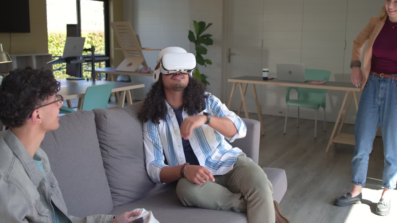 Diversi colleghi nella sala relax dell'ufficio che utilizzano visori VR e tablet per scoprire contenuti.