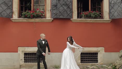 Newlyweds,-lovely-wedding-caucasian-bride-and-groom-dancing-trendy-dance-celebrating-in-city-street