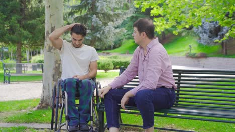 disabled young man in wheelchair is angry and mature man calming him down.