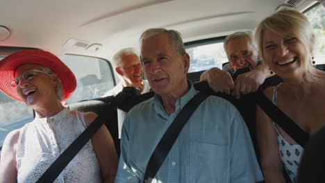 grupo de amigos mayores sentados en la parte trasera de un transportista de personas que está siendo llevado de vacaciones
