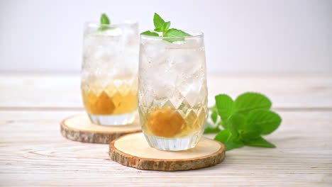 Jugo de ciruela helado con soda y menta en la mesa de madera - bebida refrescante