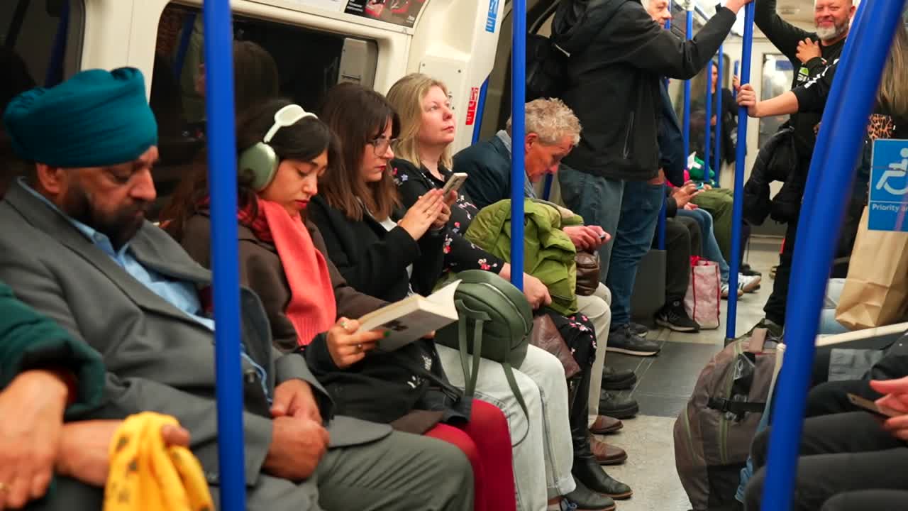 Passengers from diverse backgrounds ride the London Underground train, engaging in various activities