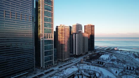 desceding aerial - lake michigan and part of chicago buildings with lakeshore drive in view, aerial at the sunset