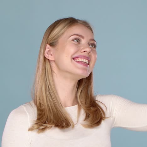 Portrait-of-a-cheerful-young-girl-with-adorable-smile-taking-selfie-isolated-over-blue-background