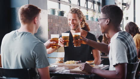 Drei-Junge-Männliche-Freunde-Treffen-Sich-Zu-Getränken-Und-Essen-Und-Stoßen-Im-Restaurant-An