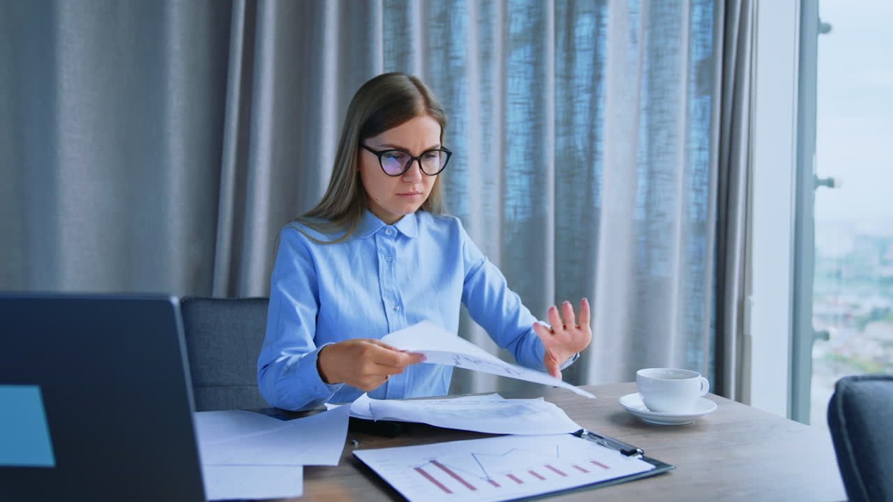 Busy annoyed business lady sitting at desk looking through the papers throwing them away. Portrait of a woman irritated by her work. Close up.