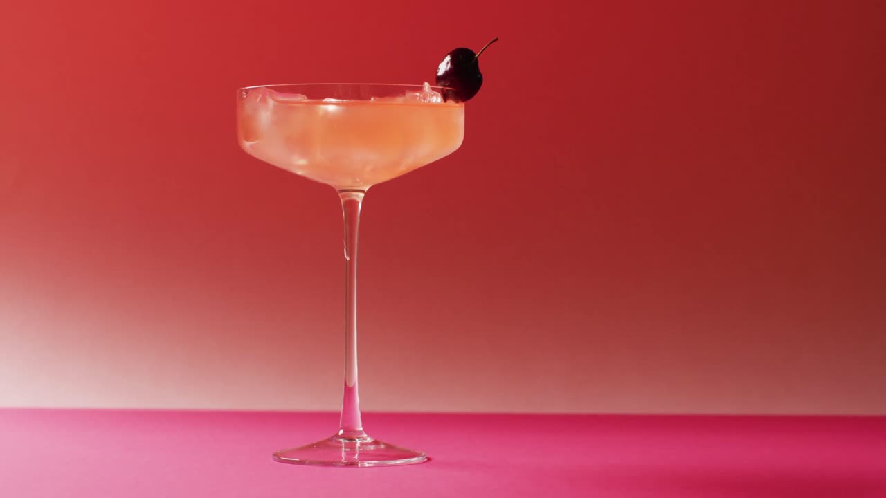 Close up of drink with cherry on pink background