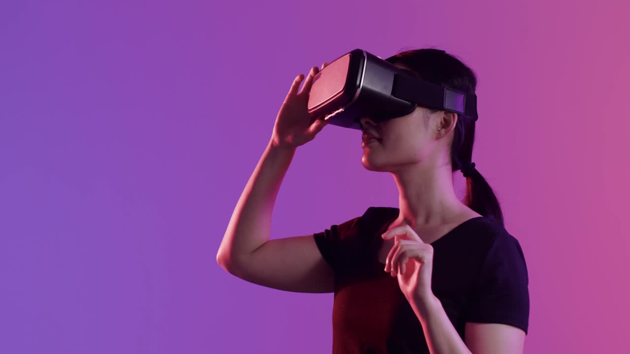 donna asiatica che usa le cuffie vr, touch screen su sfondo viola, spazio di copia, slow motion