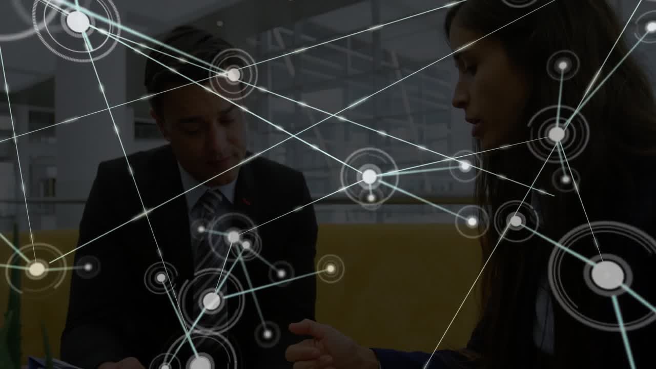 Seated colleagues pointing tablet in office, initiating expanding network overlay analyzing data