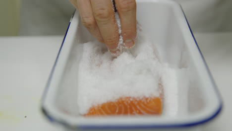 caucasian male chef pickles salmon fillet in brine,close up shot