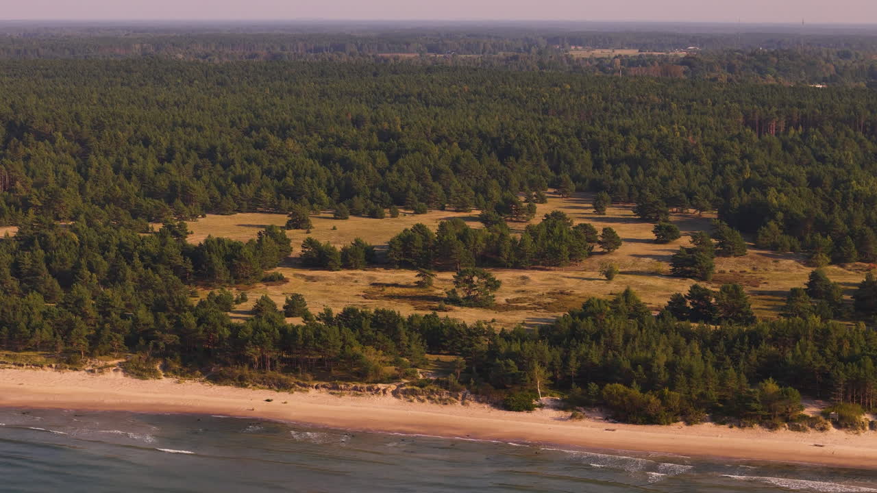 Aerial view of Pavilosta’s grey dunes, lush forests, and tranquil coastline in Latvia.