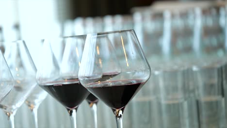 gentle hand pick up transperent glass of red wine out of other glasses