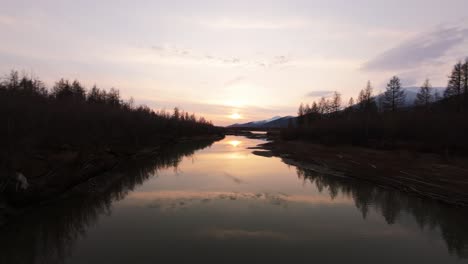 experience the tranquility of a river meandering through lush forests as the sun sets, casting golden hues across the water’s reflective surface. nature unveils its calm elegance.