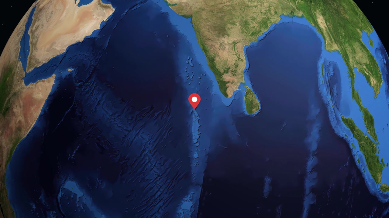 Digital globe rotates and zooms from space to a specific location marker in the Maldives