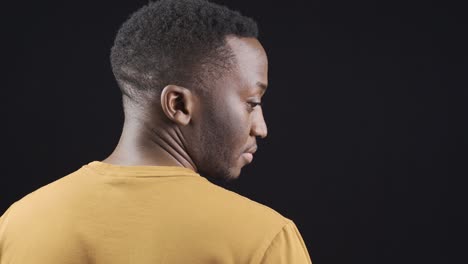 african young man with head down looking sideways feeling bad, sad and helpless.