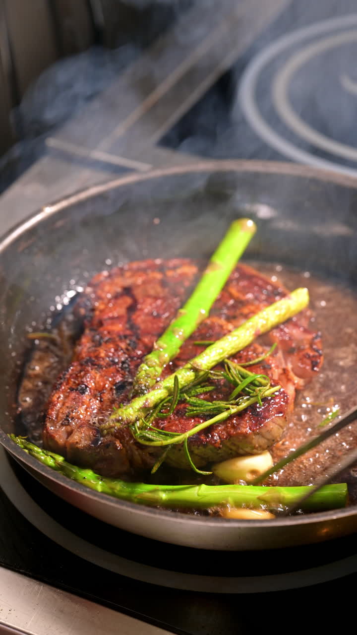 Steak in frying pan with asparagus and garlic. Closeup of grilled steak cooked in pan with asparagus and garlic cloves