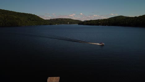 Toma-Aérea-De-Un-Barco-Que-Pasa-Y-Crea-Olas-En-Un-Lago,-Día-De-Verano