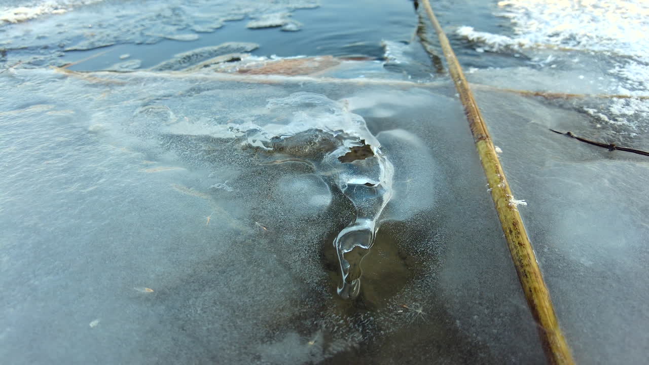 Jelajahi formasi es yang memukau dan keindahan alam di sepanjang tepi sungai. Amati lanskap musim dingin yang damai dengan elemen beku dan perairan tenang, yang memperindah pemandangan.