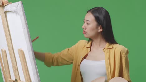 초록색 스크린 스튜디오에서 기둥 위에 그림을 그리는 여자
