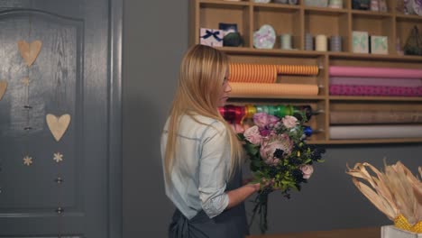 young attractive florist starting to arrange modern bouquet in the flower shot, young handsome florists work at flowers shot