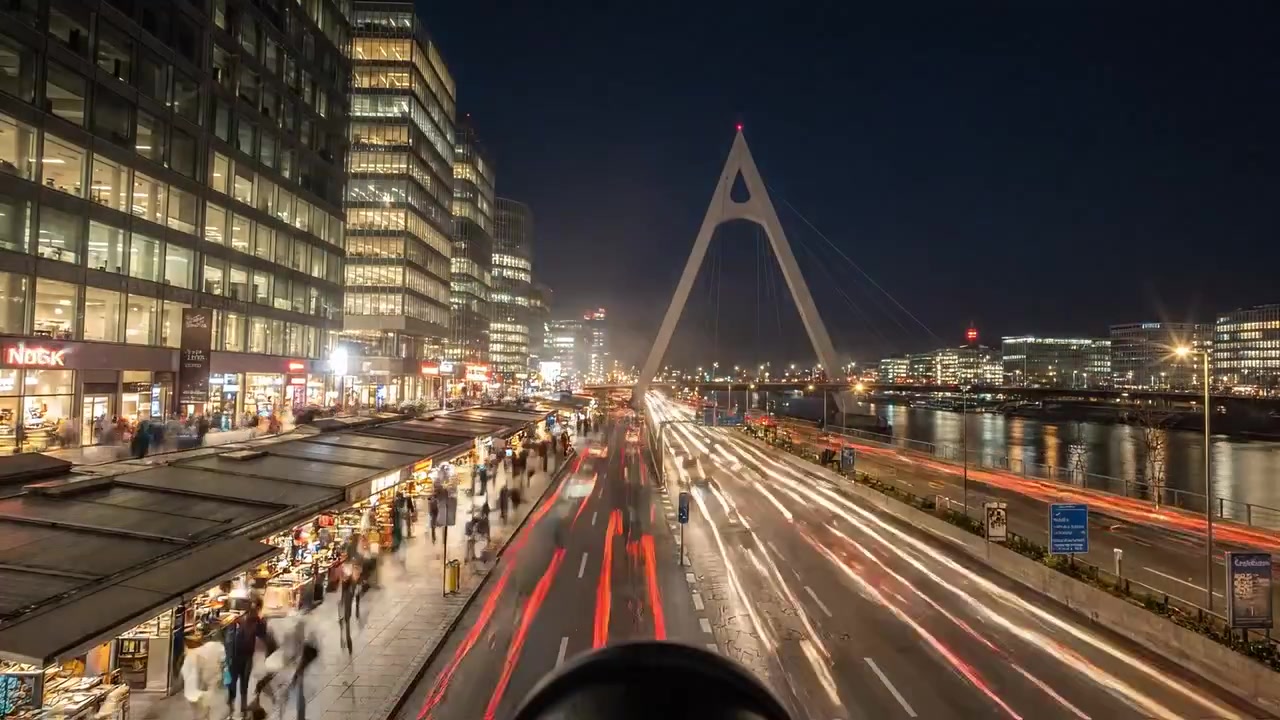 Vibrant Street Scene at Day and Night: A Look at Pedestrian Life, Blooming Flora, Urban Architecture, and Traffic Flow by a River Under a Beautiful Modern Bridge