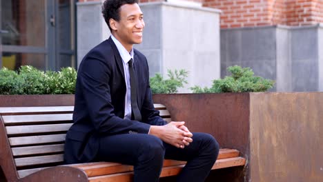 smiling african businessman winking eye while looking at camera