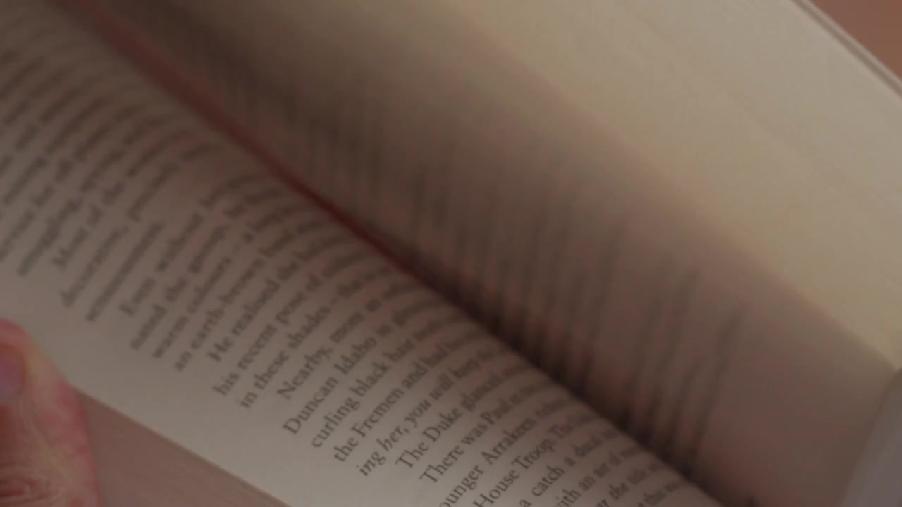 Person flipping through book pages in soft indoor lighting
