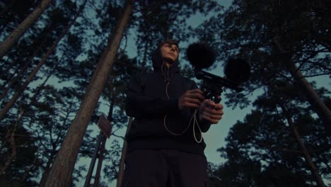 young person recording audio in the woods
