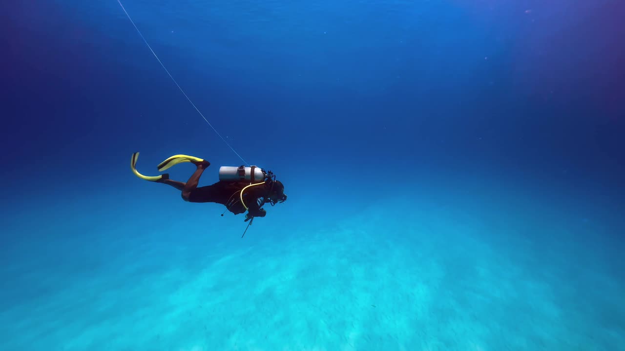 Diver using a dive reel while diving with a current. Mnemba Island, Zanzibar, Tanzania.
