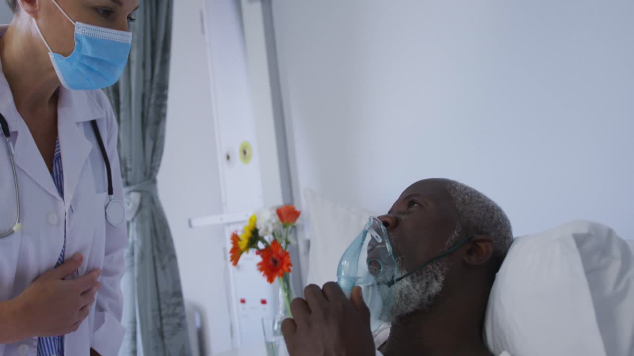 paciente masculino afroamericano en una cama de hospital con una máscara de oxígeno hablando con el médico