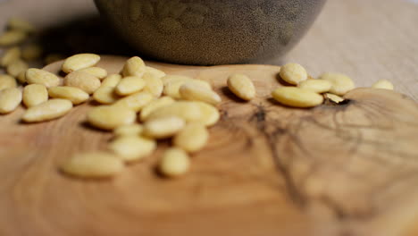 close up shot of blanched almond nuts revolving next to bowl