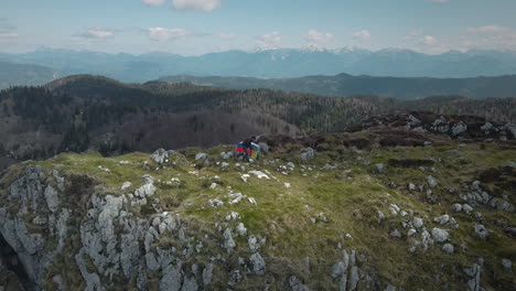 Drone-shot-of-a-hiker-at-the-top-of-mountain-Ratitovec-with-a-slovenian-flag