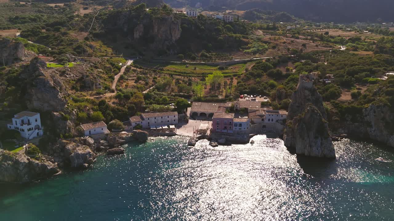 Static aerial drone shot showing the entire coastline and vibrant green nature of Scopello, Sicily, Italy, highlighting the Mediterranean landscape during Italian summer