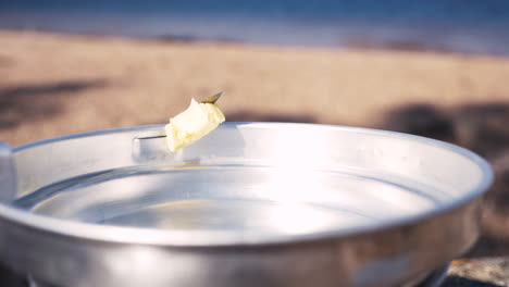 Close-up-of-girl-putting-butter-in-a-pan-of-a-Trangia-portable-stove,-butter-starts-to-melt