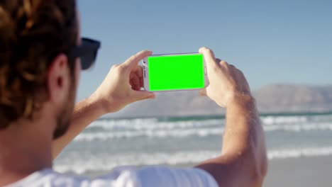 Man-taking-photo-with-mobile-phone-at-beach