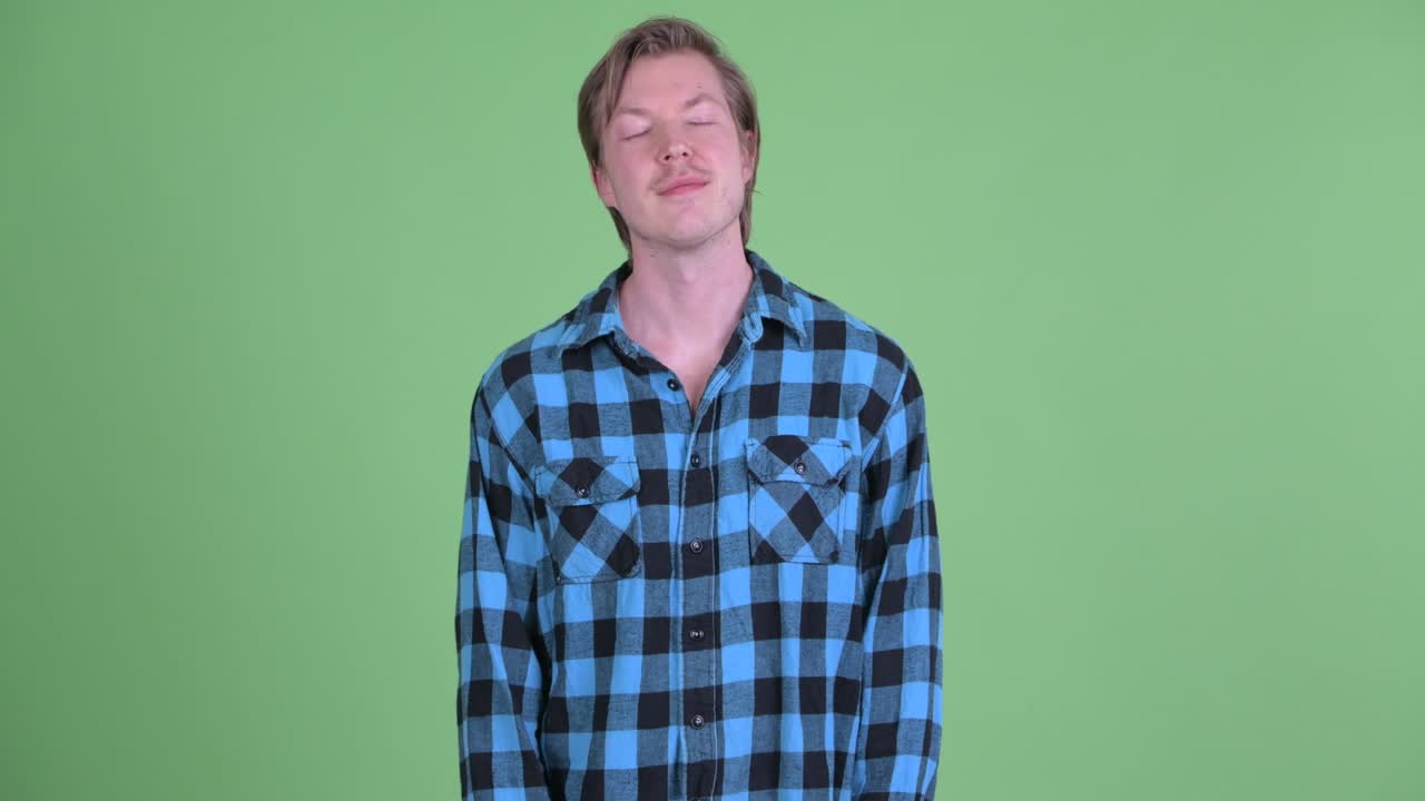 녹색 스튜디오 배경에 눈을 감고 미소 짓고 꿈꾸는 백인 남자의 초상화