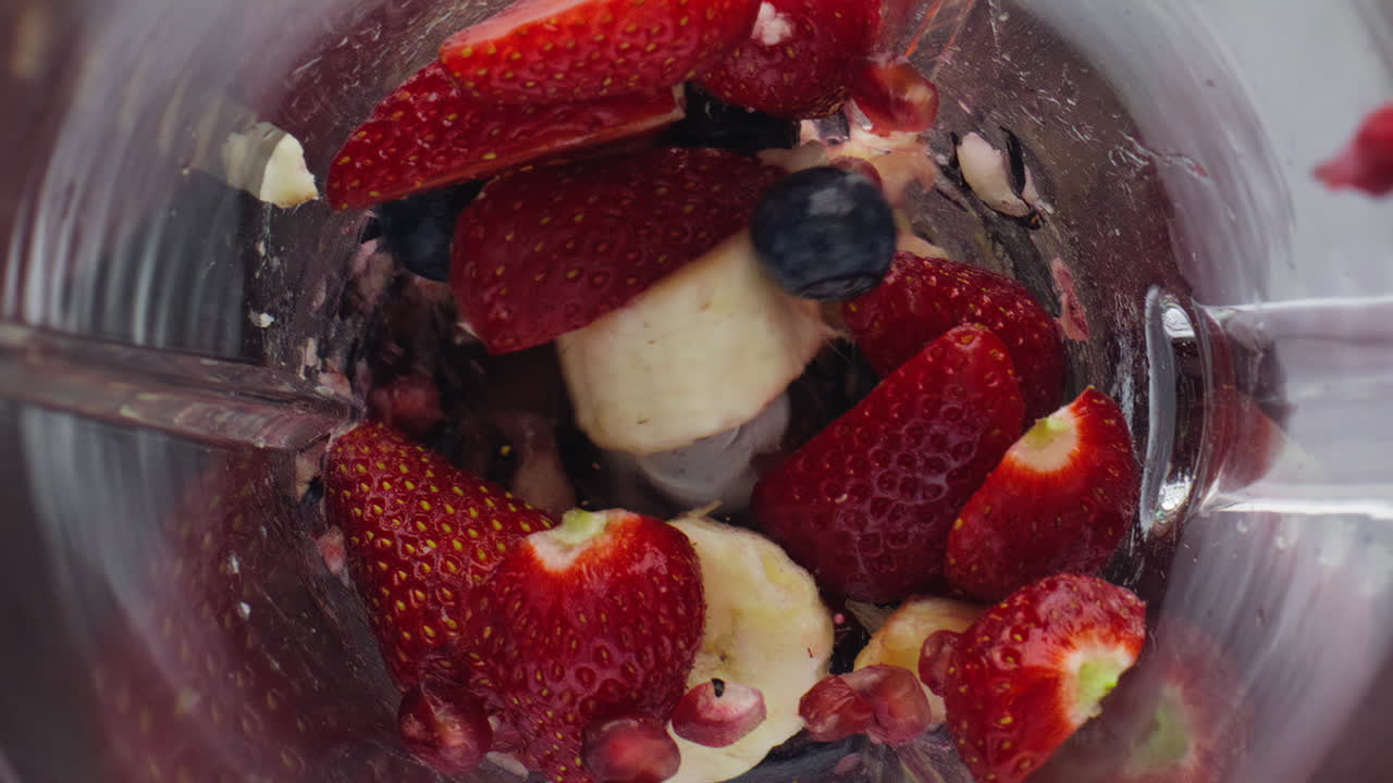 Frullatore che sminuzza frutti di bosco freschi al rallentatore, primo piano. Ingredienti succosi.