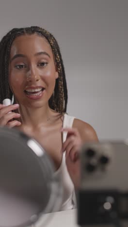 joven grabando belleza maquillaje revisión o tutorial para lápiz labial en teléfono móvil para cargar en el canal de redes sociales 2