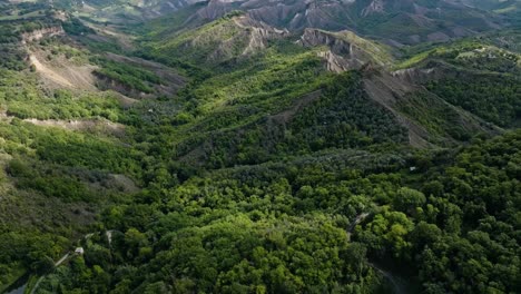 Aerial-over-the-wooded-valleys-near-the-hilltop-village-of-Civita-di-Bagnoregio,-Province-of-Viterbo,-Italy