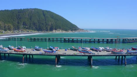 Puerto-O-Caleta-Meguellines,-Constitución-Chile-Drone-Tiro-Día-Soleado-Con-Barcos-De-Pesca-Que-Viajan-A-La-Izquierda