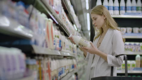 publicidade de negócios de alimentos conceito de saúde - mulher em um supermercado de pé na frente do congelador e escolher comprar garrafa de leite fresco. beber leite para saudável.