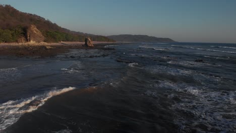 the beautiful waves of costa rica rolling over the rocky shoreline - aerial