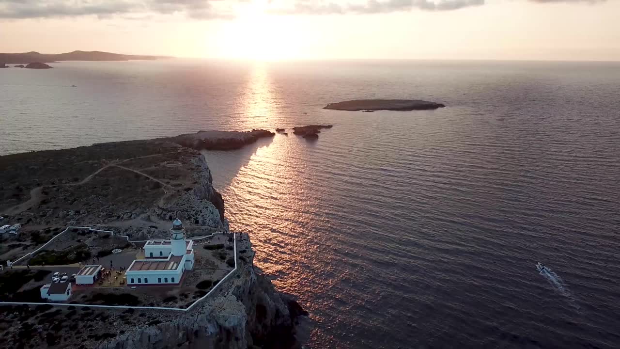 hermosa puesta de sol y faro en cabo cavalleria en la costa norte de menorca, islas baleares, españa - retroceso aéreo