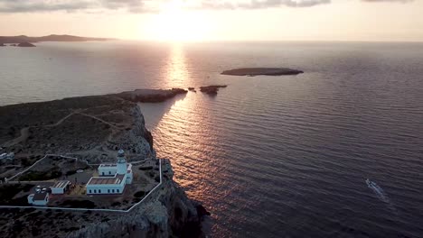 beautiful sunset and lighthouse at cape cavalleria on the north coast of menorca, balearic islands, spain - aerial pullback