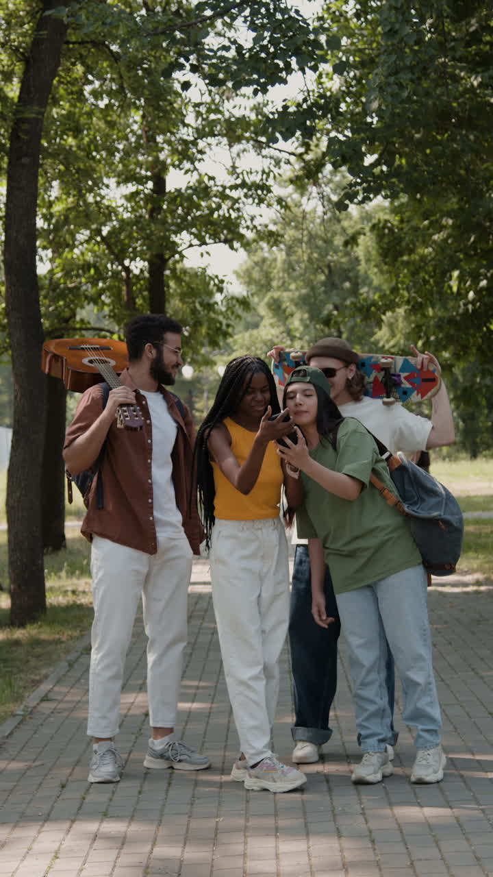 A group of young friends looking at a smartphone together in a park